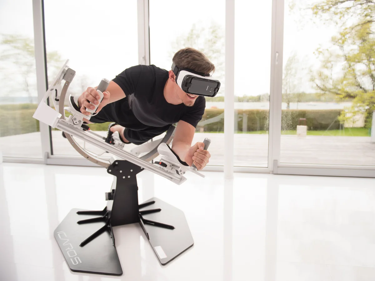 Person mit VR-Brille auf dem ICAROS-Flugsimulator beim virtuellen Flug im Naturbildungszentrum Alfsee